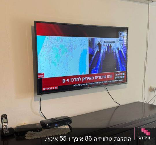 טלוויזיה על קיר עם מזגן ושלטים על שידה